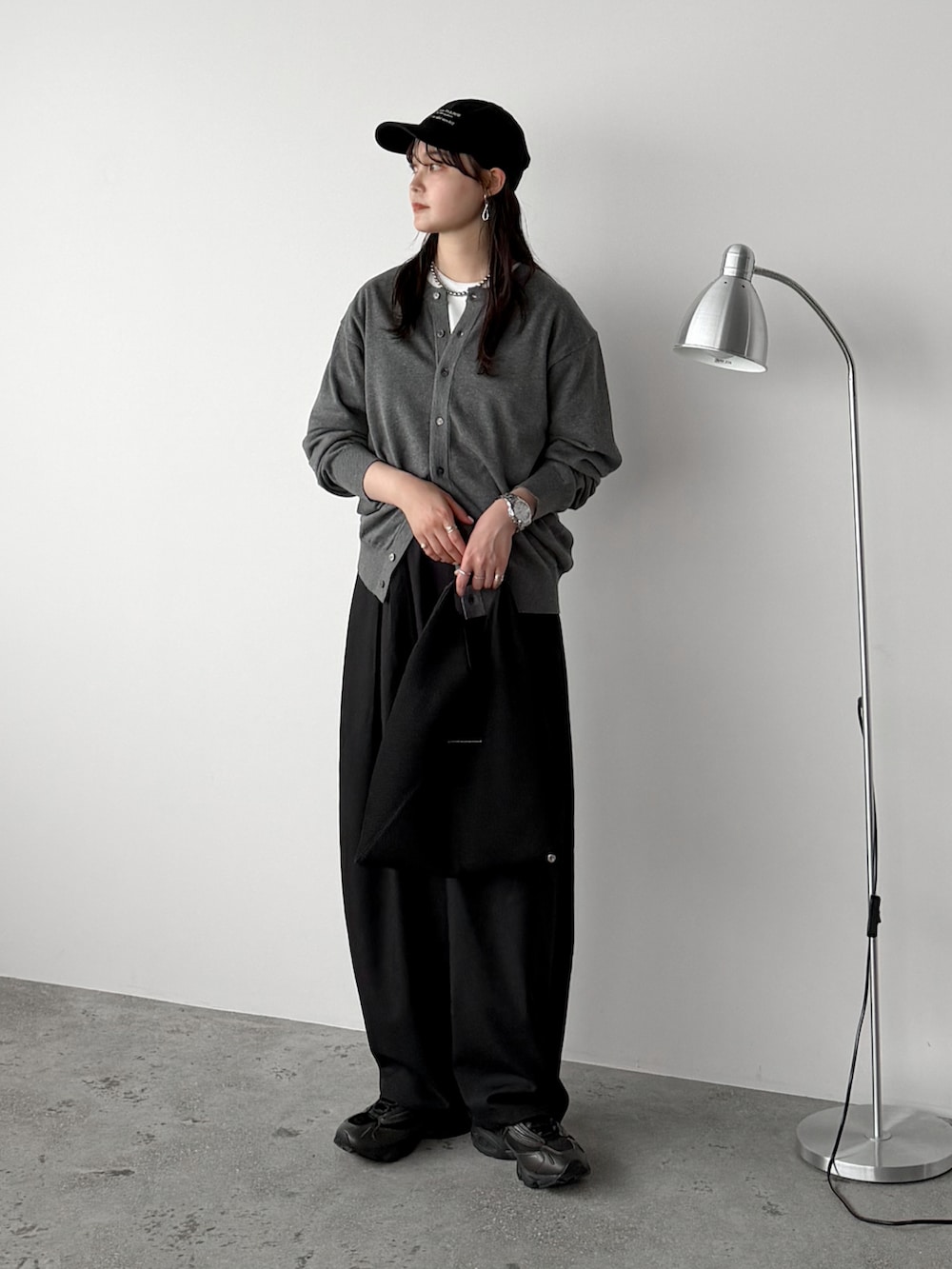 ブラック系のスラックス、グレー系のカーディガン/ボレロ、ホワイト系のTシャツ/カットソーを着用したレディースの春コーディネートの2枚目の写真