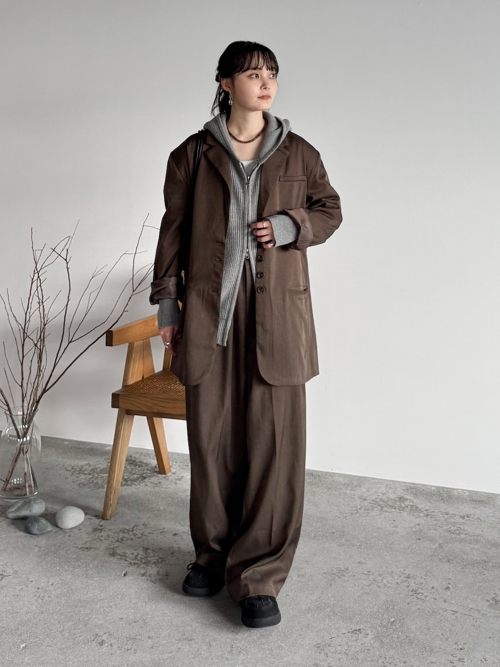 グレー系のニット/セーター、ブラウン系のテーラードジャケット、ブラウン系のスラックスを着用したレディースの秋コーディネートの2枚目の写真