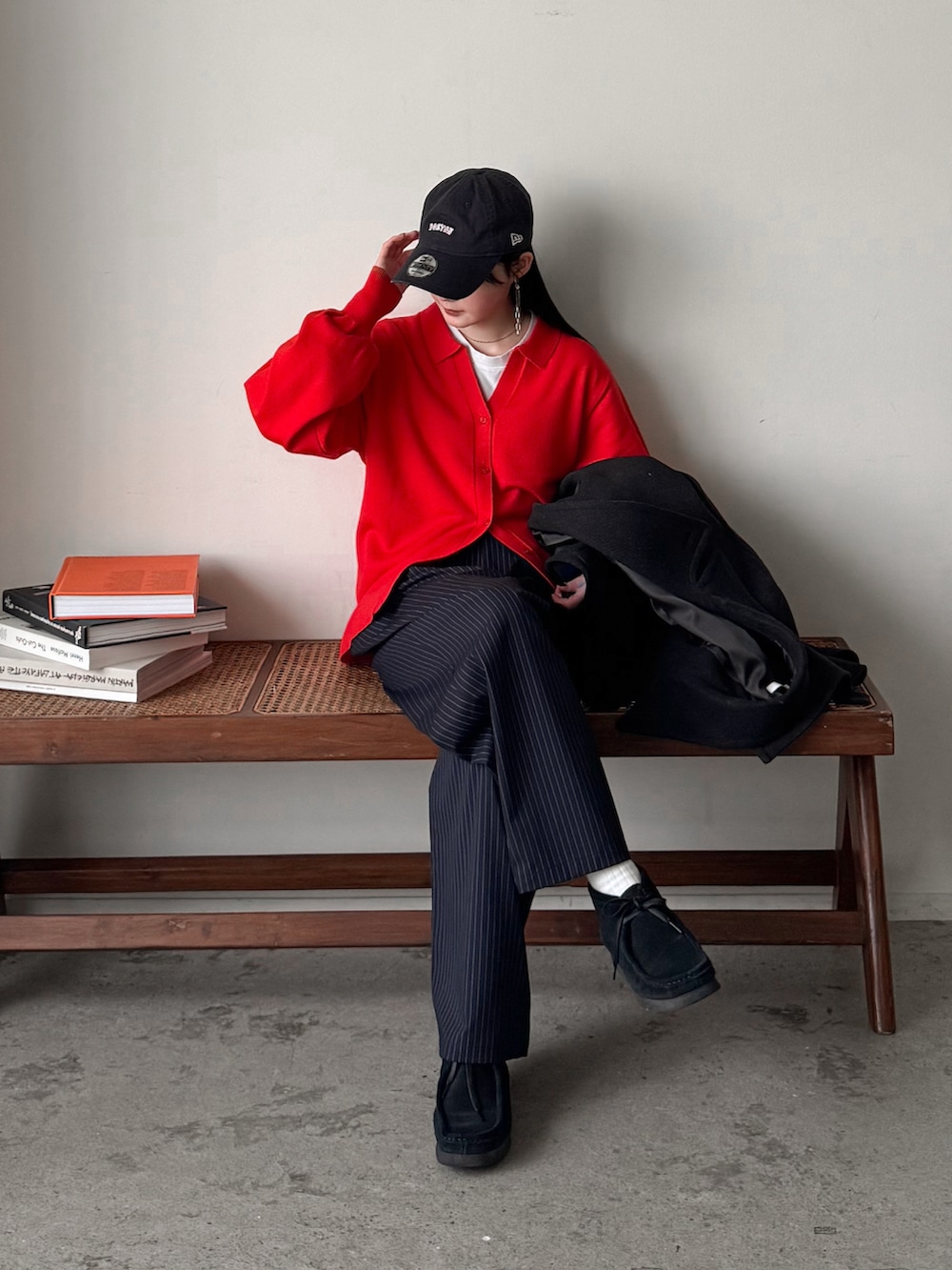 レッド系のカーディガン/ボレロ、グレー系のチェスターコート、ブルー系のスラックスを着用したレディースの冬コーディネートの2枚目の写真