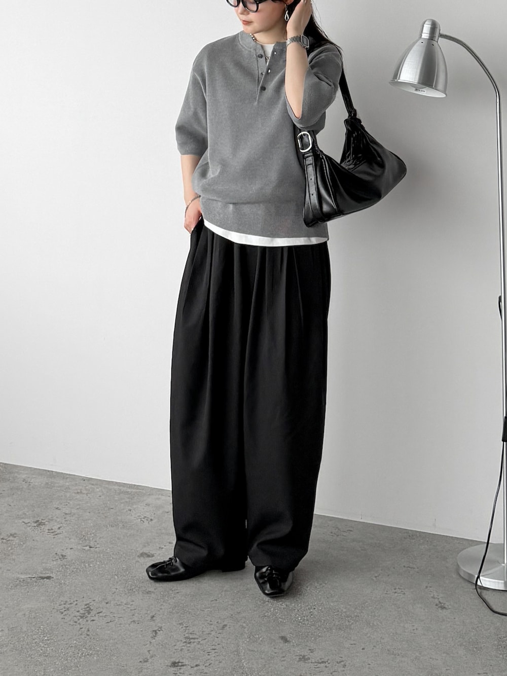 ブラック系のスラックス、グレー系のニット/セーター、ホワイト系のTシャツ/カットソーを着用したレディースの春コーディネートの2枚目の写真