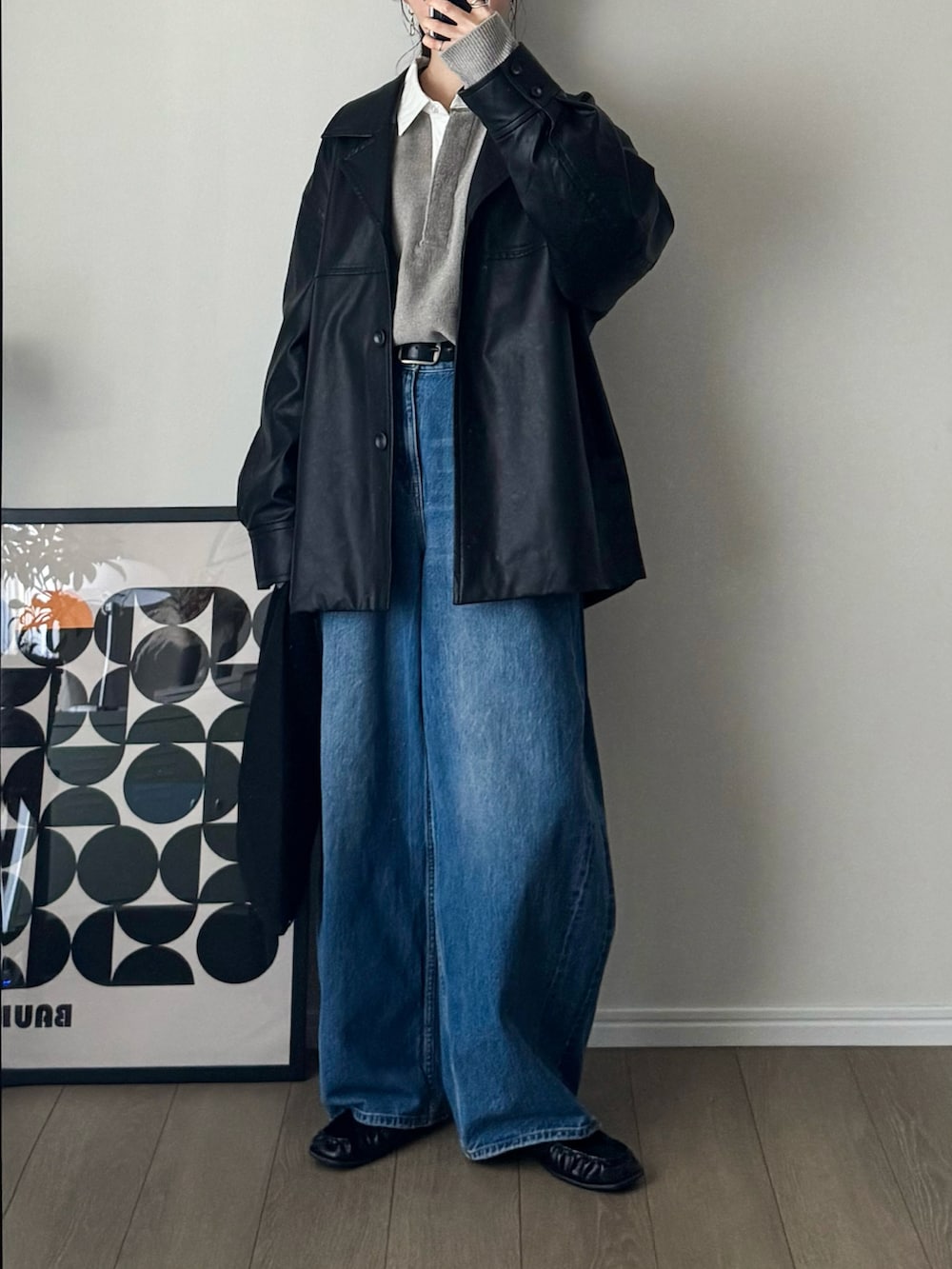 ブラック系のライダースジャケット、グレー系のニット/セーター、ブルー系のデニムパンツを着用したレディースの秋コーディネートの2枚目の写真