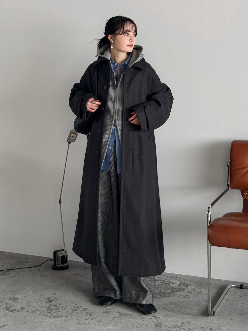 グレー系のニット/セーター、ブルー系のシャツ/ブラウス、グレー系のステンカラーコートを着用したレディースの冬コーディネートの2枚目の写真