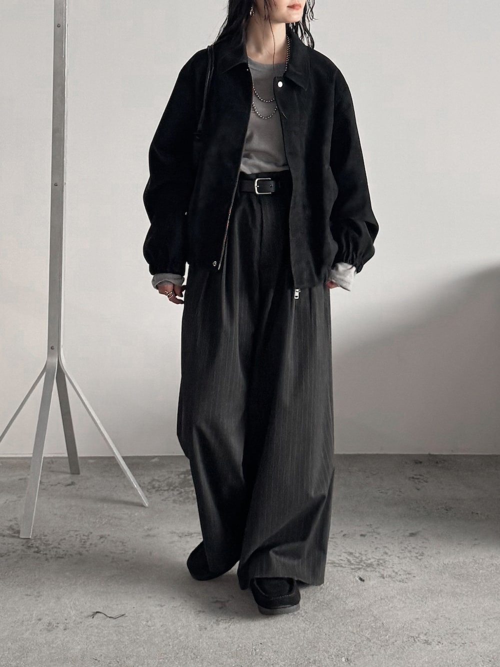 グレー系のTシャツ/カットソー、ブラック系のブルゾン、グレー系のスラックスを着用したレディースの秋コーディネートの2枚目の写真