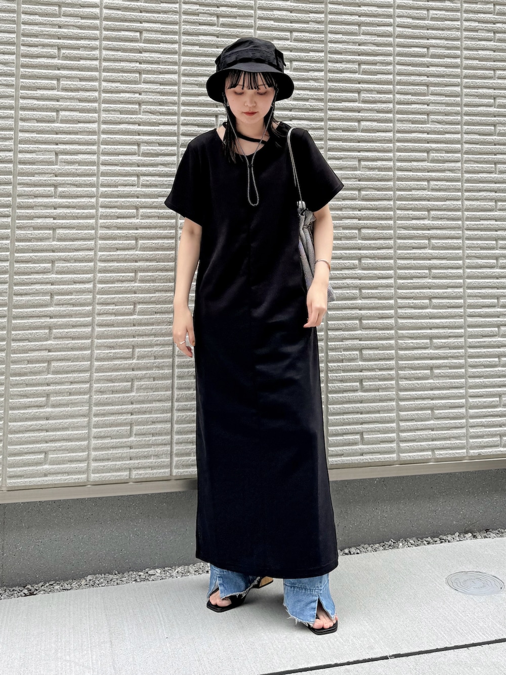 ブラック系のワンピース、ブルー系のデニムパンツ、シルバー系のショルダーバッグを着用したレディースの春コーディネートの2枚目の写真