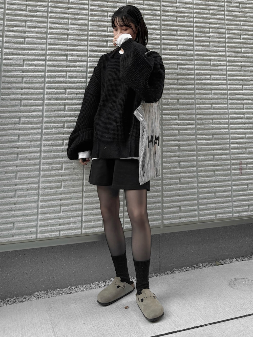 ブラック系のニット/セーター、ホワイト系のTシャツ/カットソー、ブラック系のその他パンツを着用したレディースの冬コーディネートの2枚目の写真