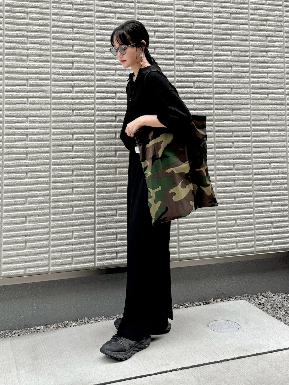 ブラック系のポロシャツ、ブラック系のスカート、グリーン系のトートバッグを着用したレディースの夏コーディネートの2枚目の写真