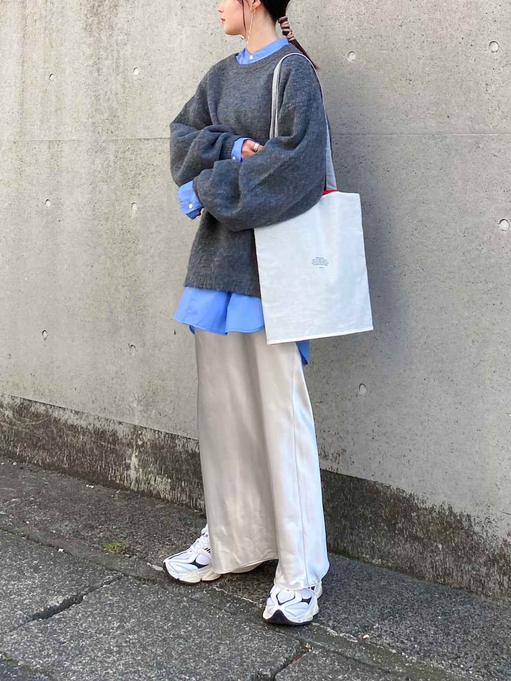 グレー系のニット/セーター、ブルー系のシャツ/ブラウス、ホワイト系のスカートを着用したレディースの秋コーディネートの2枚目の写真