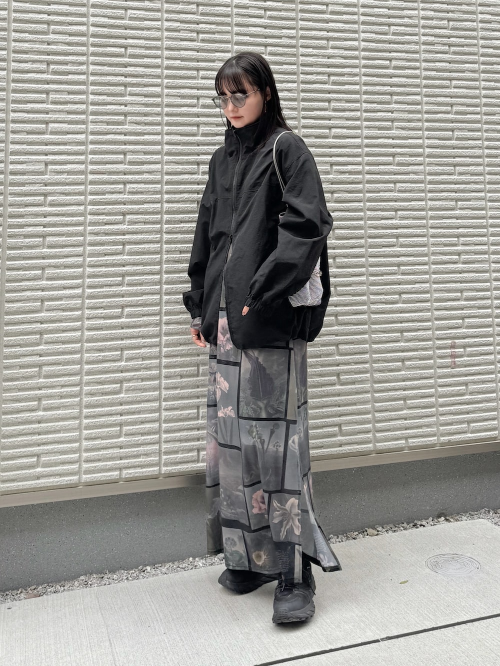 ブラック系のナイロンジャケット、ブラック系のワンピース、シルバー系のショルダーバッグを着用したレディースの春コーディネートの3枚目の写真