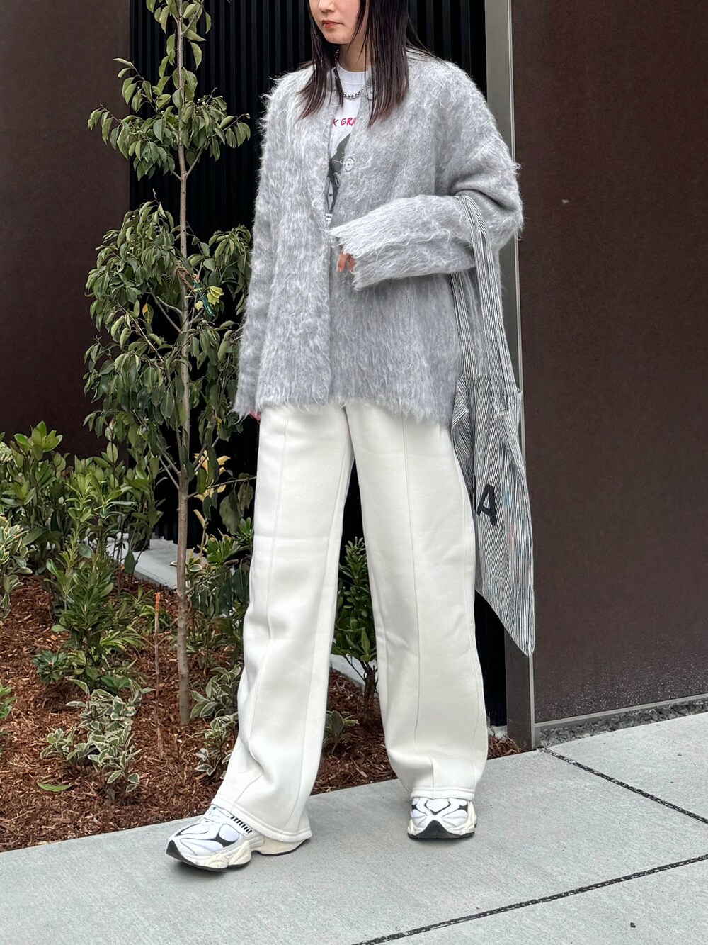 グレー系のカーディガン/ボレロ、ホワイト系のTシャツ/カットソー、ホワイト系のスニーカーを着用したレディースの冬コーディネートの2枚目の写真