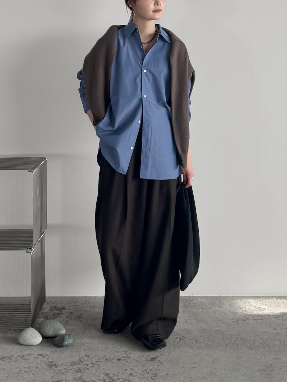 ブラウン系のスラックス、ブルー系のシャツ/ブラウス、ブラウン系のニット/セーターを着用したレディースの秋コーディネートの2枚目の写真