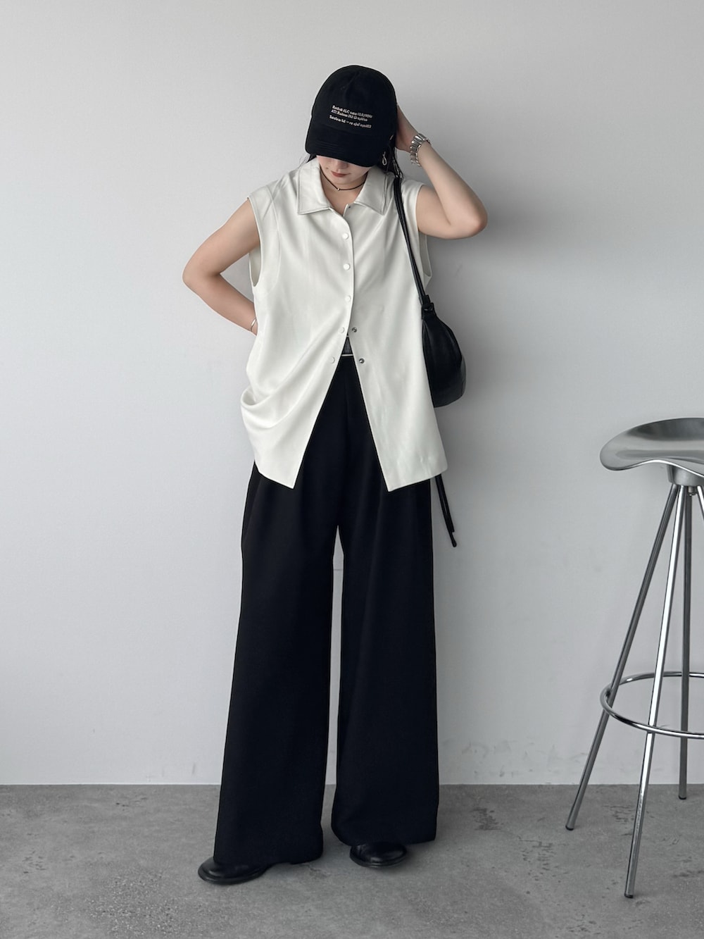 ホワイト系のベスト、ブラック系のスラックス、ブラック系のショルダーバッグを着用したレディースの夏コーディネートの2枚目の写真