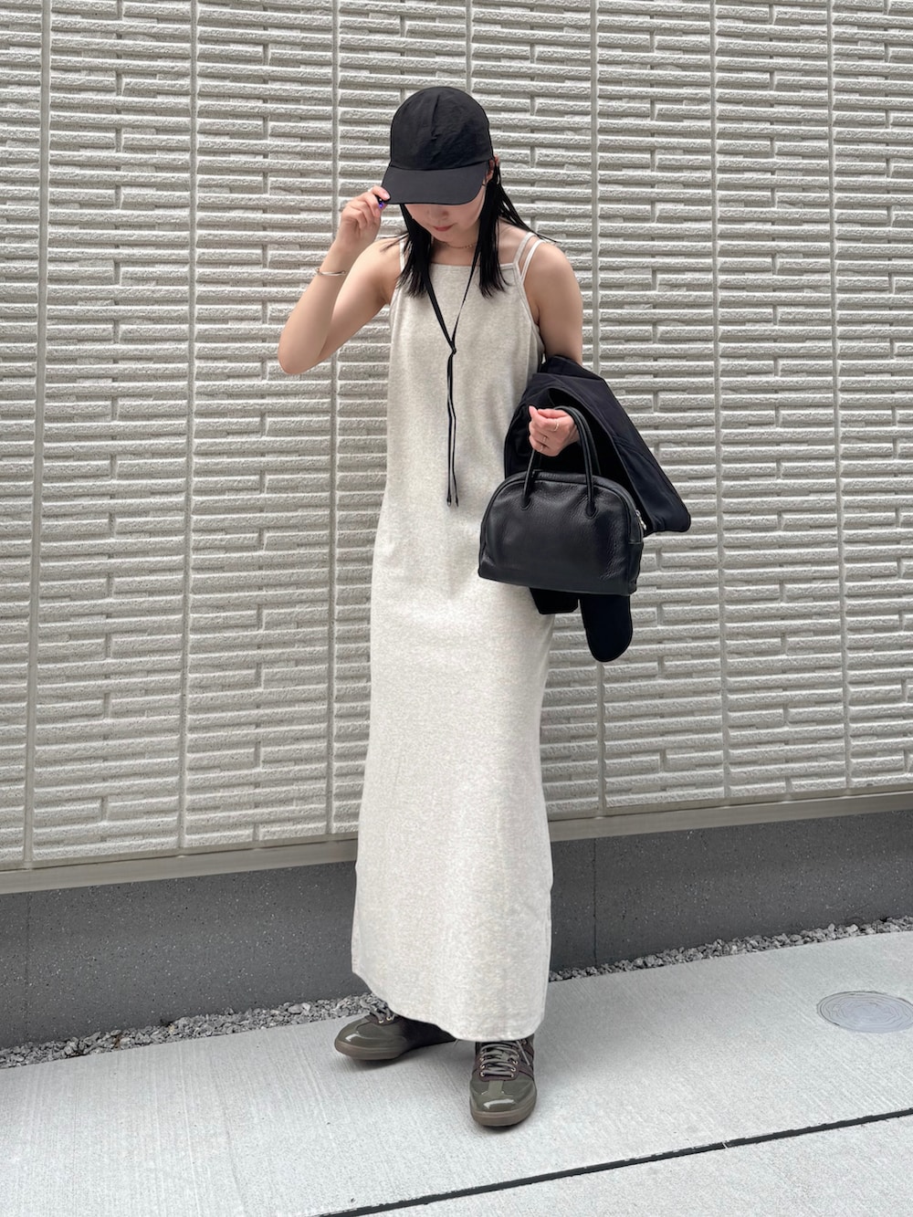 ベージュ系のワンピース、ブラック系のベスト、ブラック系のショルダーバッグを着用したレディースの夏コーディネートの3枚目の写真