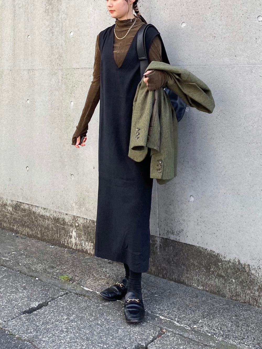 ブラック系のジャンパースカート、グリーン系のテーラードジャケット、ブラウン系のTシャツ/カットソーを着用したレディースの秋コーディネートの2枚目の写真