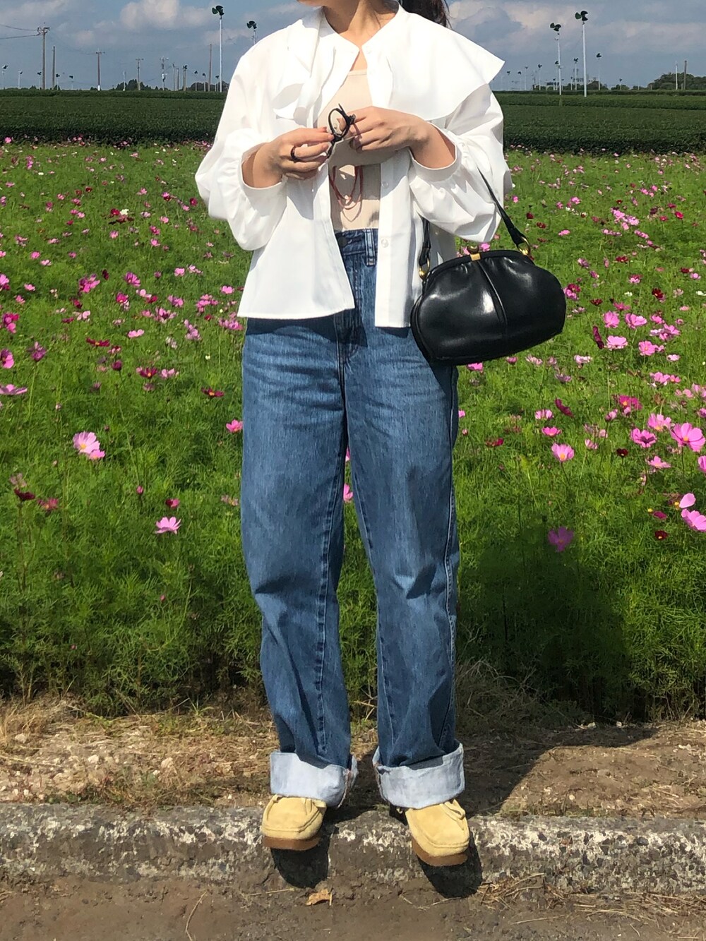 ブルー系のデニムパンツ、ベージュ系のモカシン/デッキシューズ、ブラック系のトートバッグを着用したレディースの秋コーディネートの3枚目の写真