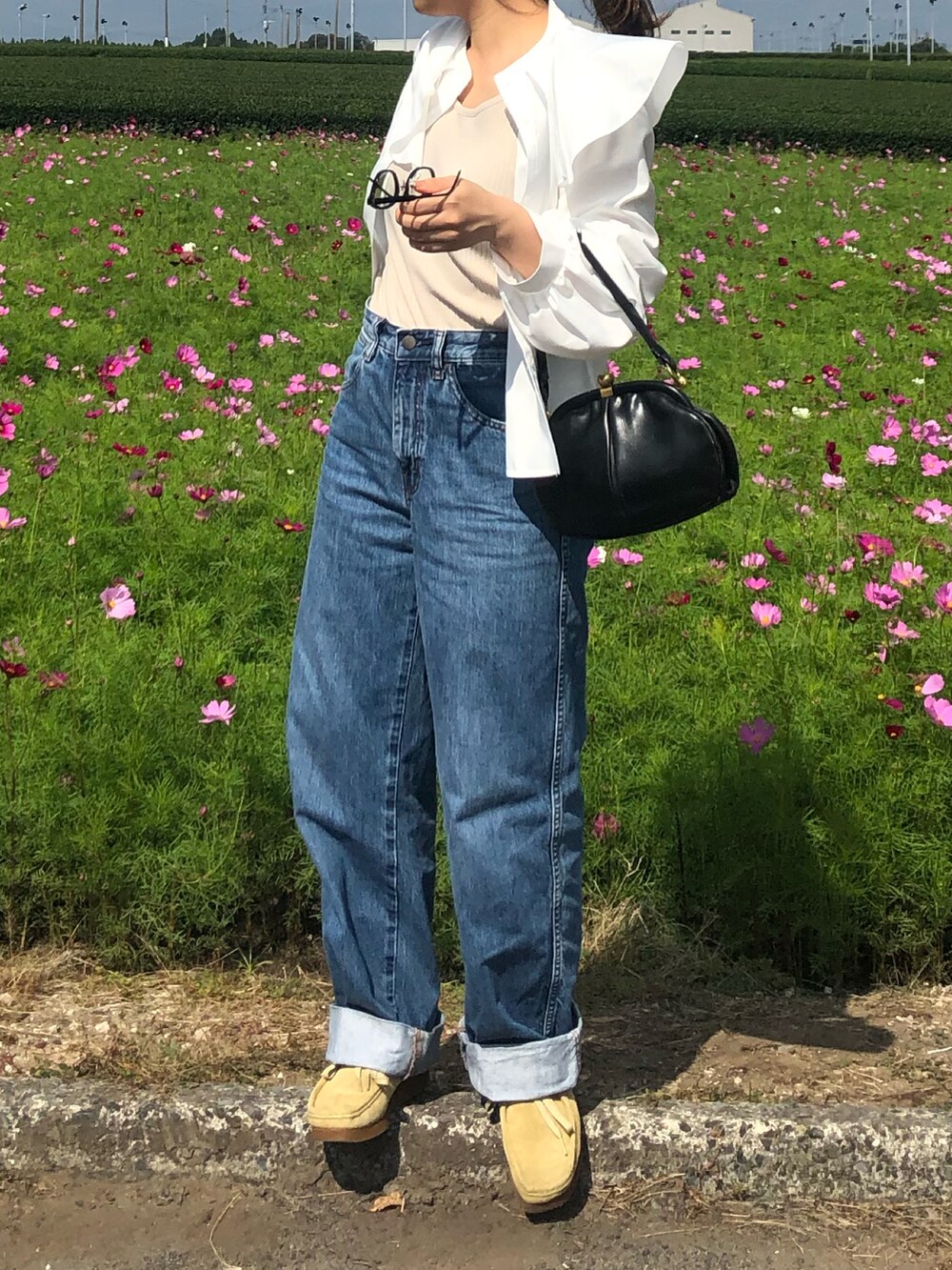 ブルー系のデニムパンツ、ベージュ系のモカシン/デッキシューズ、ブラック系のトートバッグを着用したレディースの秋コーディネートの2枚目の写真