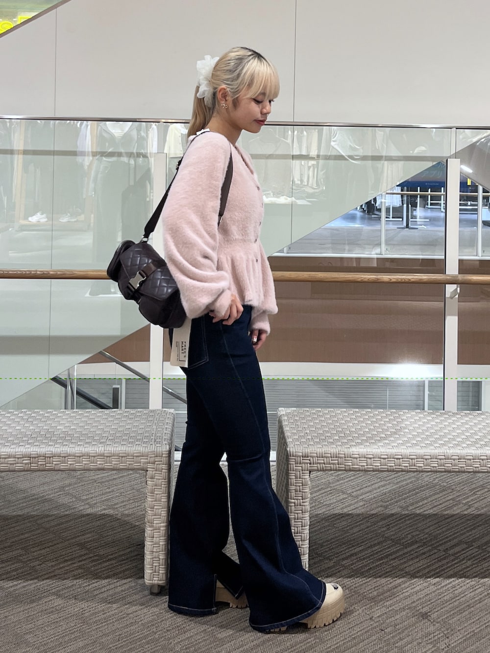 ブルー系のデニムパンツ、ブラウン系のショルダーバッグ、ピンク系のニット/セーターを着用したレディースの秋コーディネートの2枚目の写真