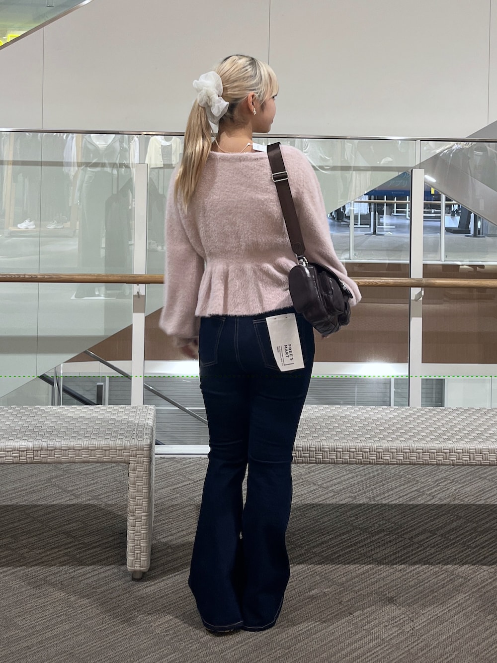 ブルー系のデニムパンツ、ブラウン系のショルダーバッグ、ピンク系のニット/セーターを着用したレディースの秋コーディネートの3枚目の写真