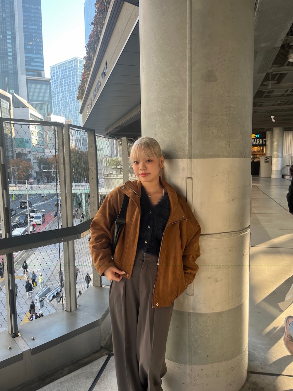 グレー系のスラックス、ブラウン系のブルゾン、ブルー系のニット/セーターを着用したレディースの秋コーディネートの2枚目の写真