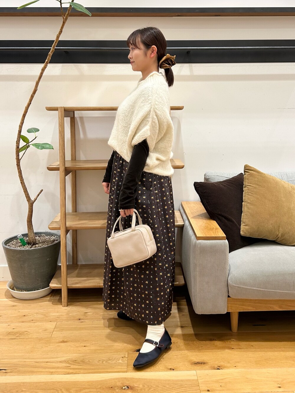 ホワイト系のニット/セーター、ブラウン系のTシャツ/カットソー、グレー系のボストンバッグを着用したレディースの秋コーディネートの2枚目の写真