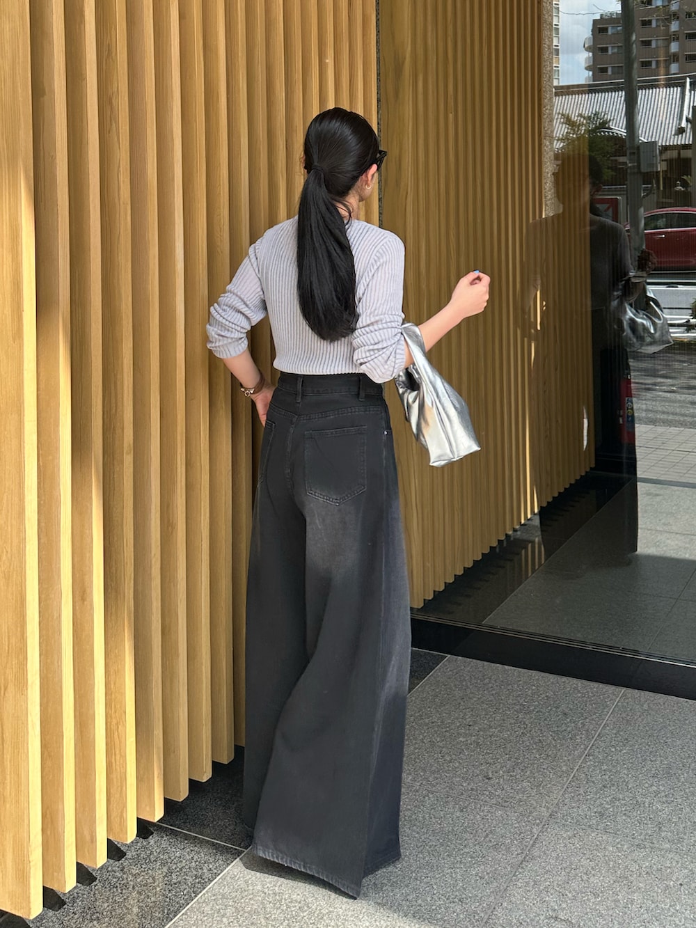 ブラック系のデニムパンツ、シルバー系のハンドバッグ、グレー系のニット/セーターを着用したレディースの春コーディネートの3枚目の写真