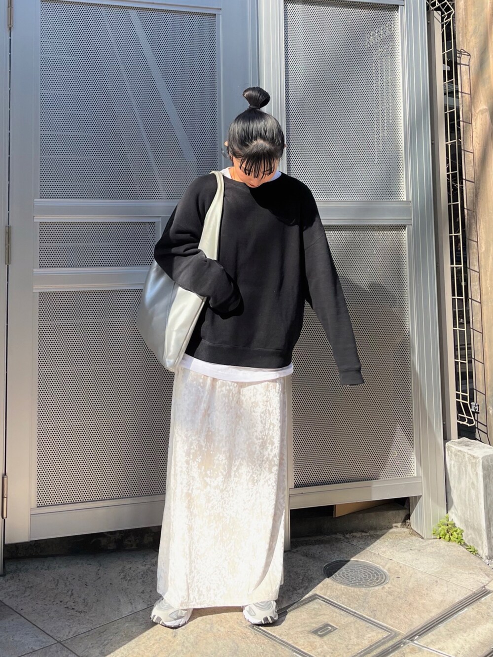 ベージュ系のスカート、ブラック系のスウェット、シルバー系のトートバッグを着用したレディースの冬コーディネートの2枚目の写真