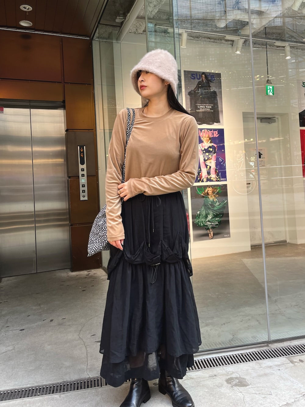 ブラウン系のTシャツ/カットソー、ブラック系のスカート、ベージュ系のハットを着用したレディースの冬コーディネートの4枚目の写真