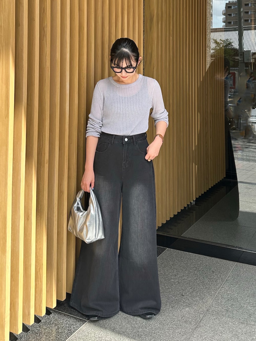 ブラック系のデニムパンツ、シルバー系のハンドバッグ、グレー系のニット/セーターを着用したレディースの春コーディネートの2枚目の写真