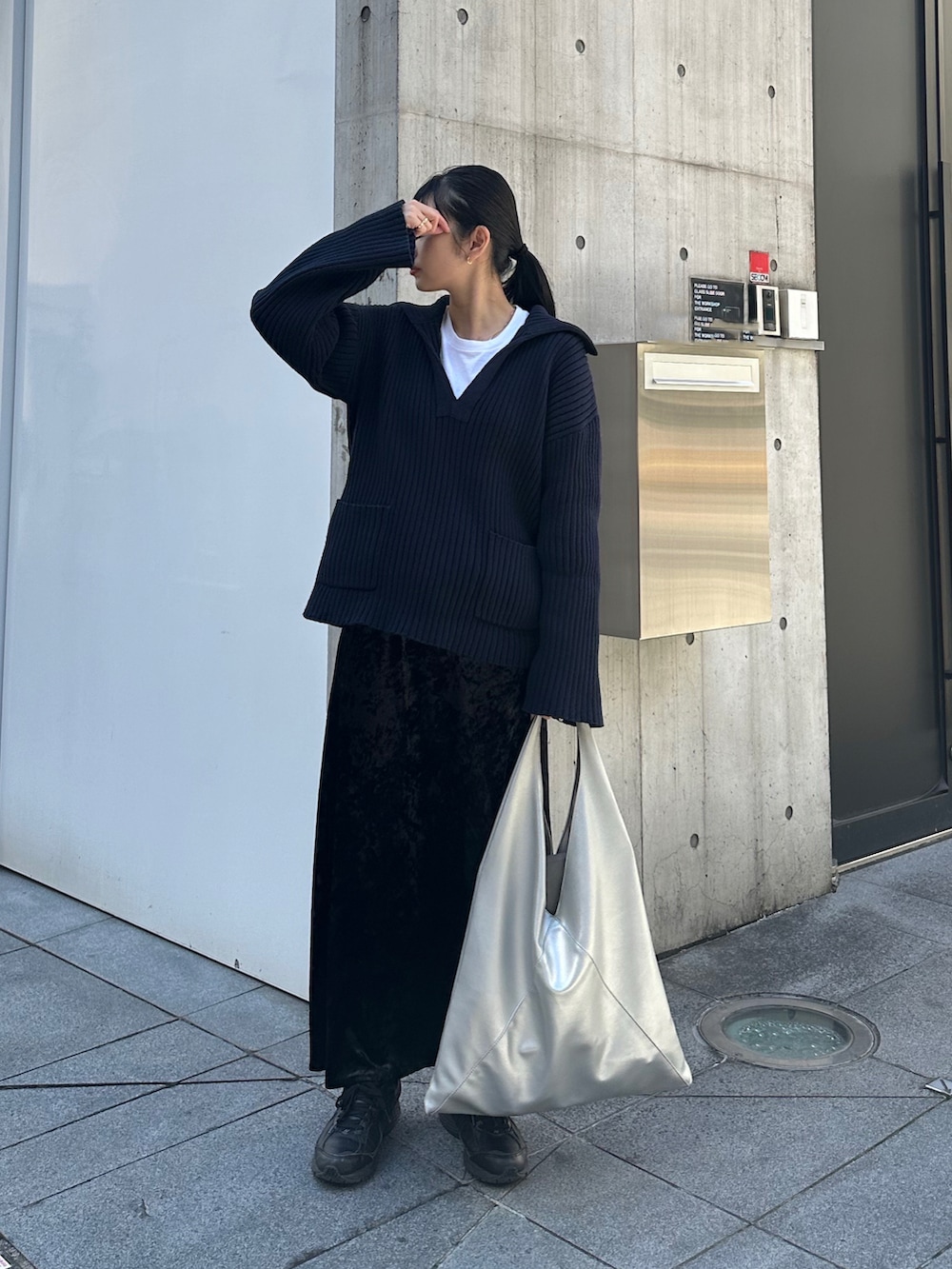 シルバー系のトートバッグ、ブラック系のスカート、ブラック系のスニーカーを着用したレディースの春コーディネートの2枚目の写真