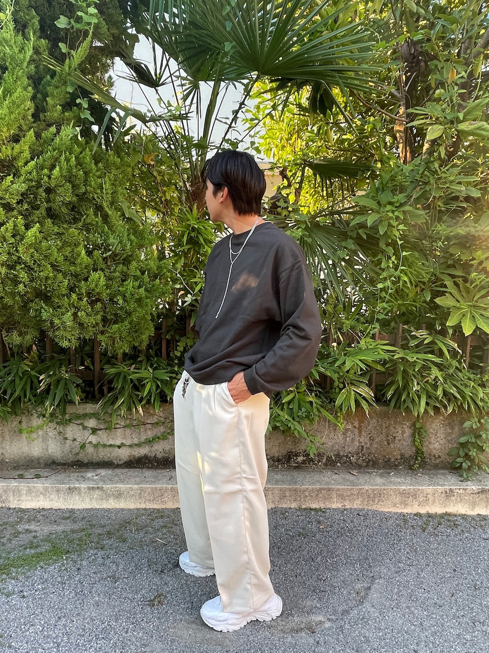 ブラック系のTシャツ/カットソー、ベージュ系のスラックス、ホワイト系のスニーカーを着用したメンズの秋コーディネートの2枚目の写真