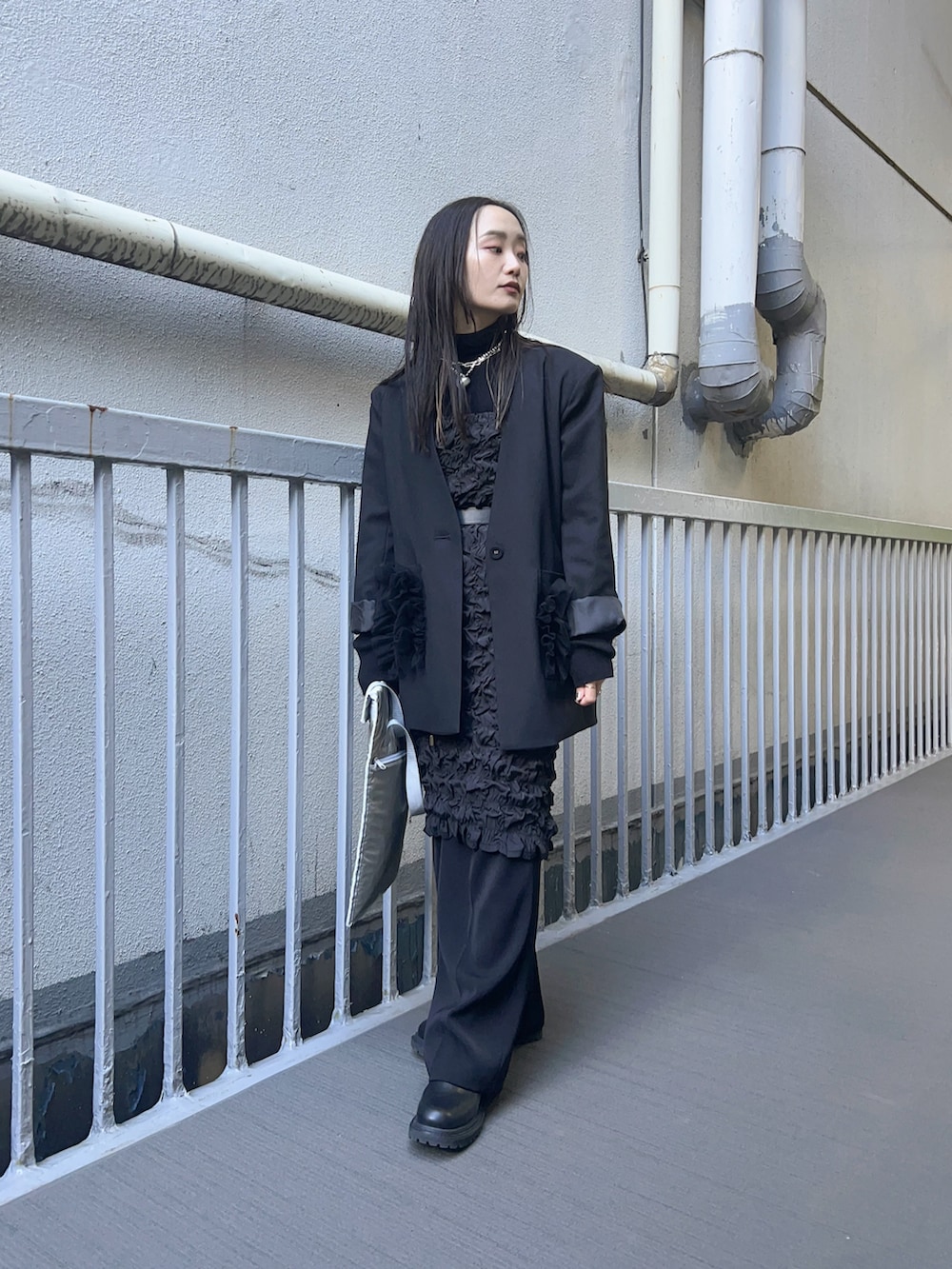 ブラック系のスカート、ブラック系のニット/セーター、ブラック系のブーツを着用したレディースの春コーディネートの2枚目の写真