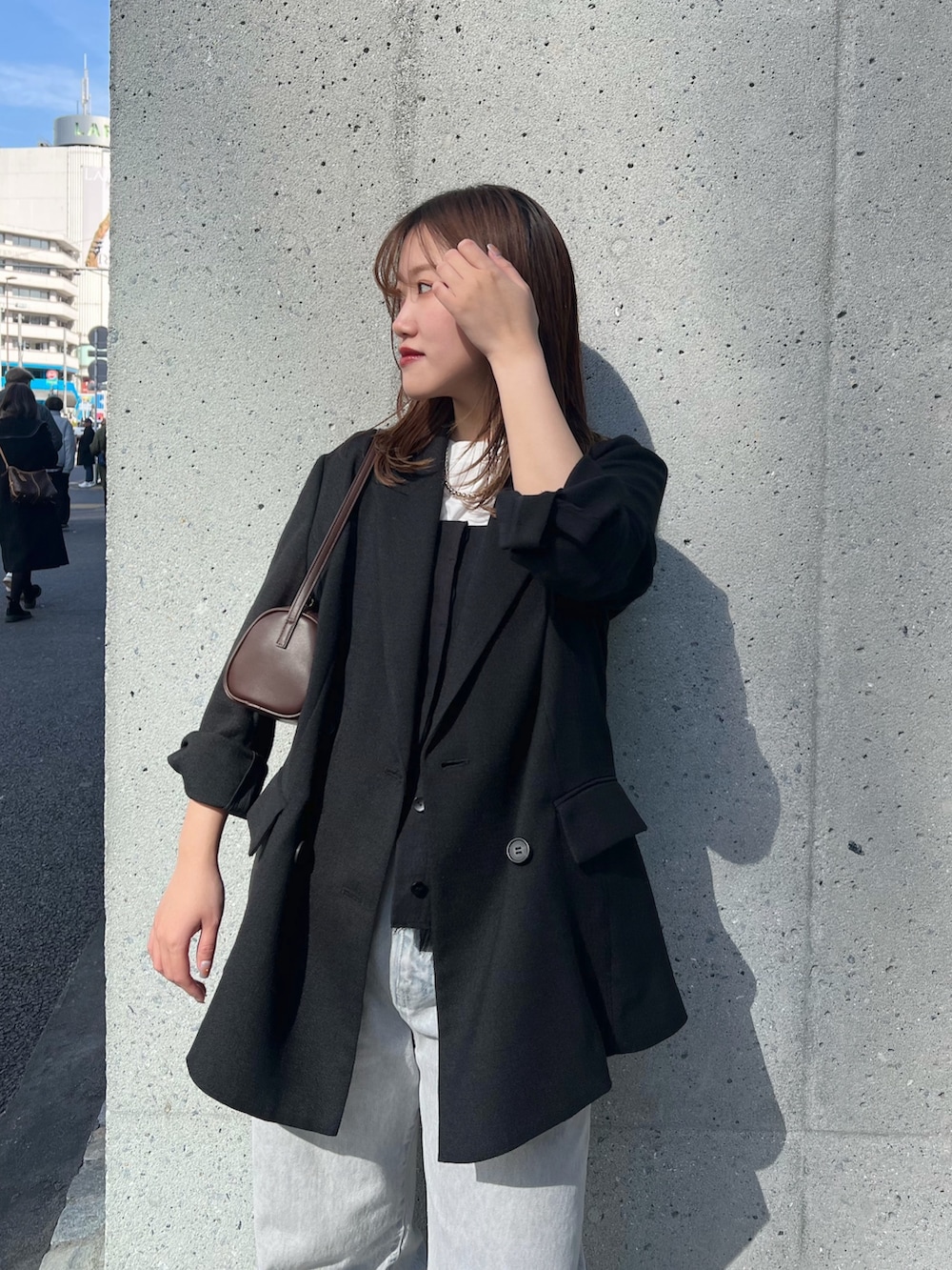 ブラック系のテーラードジャケット、グレー系のデニムパンツ、ブラウン系のショルダーバッグを着用したレディースの冬コーディネートの2枚目の写真