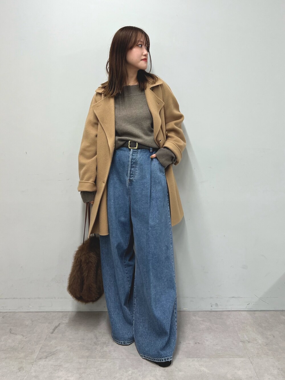 ブラウン系のニット/セーター、イエロー系のピーコート、ブルー系のデニムパンツを着用したレディースの秋コーディネートの2枚目の写真