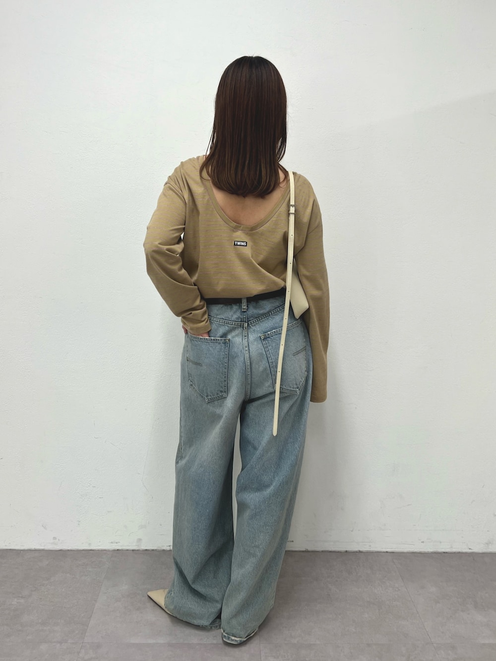 ベージュ系のTシャツ/カットソー、ブルー系のデニムパンツ、ホワイト系のショルダーバッグを着用したレディースの冬コーディネートの2枚目の写真