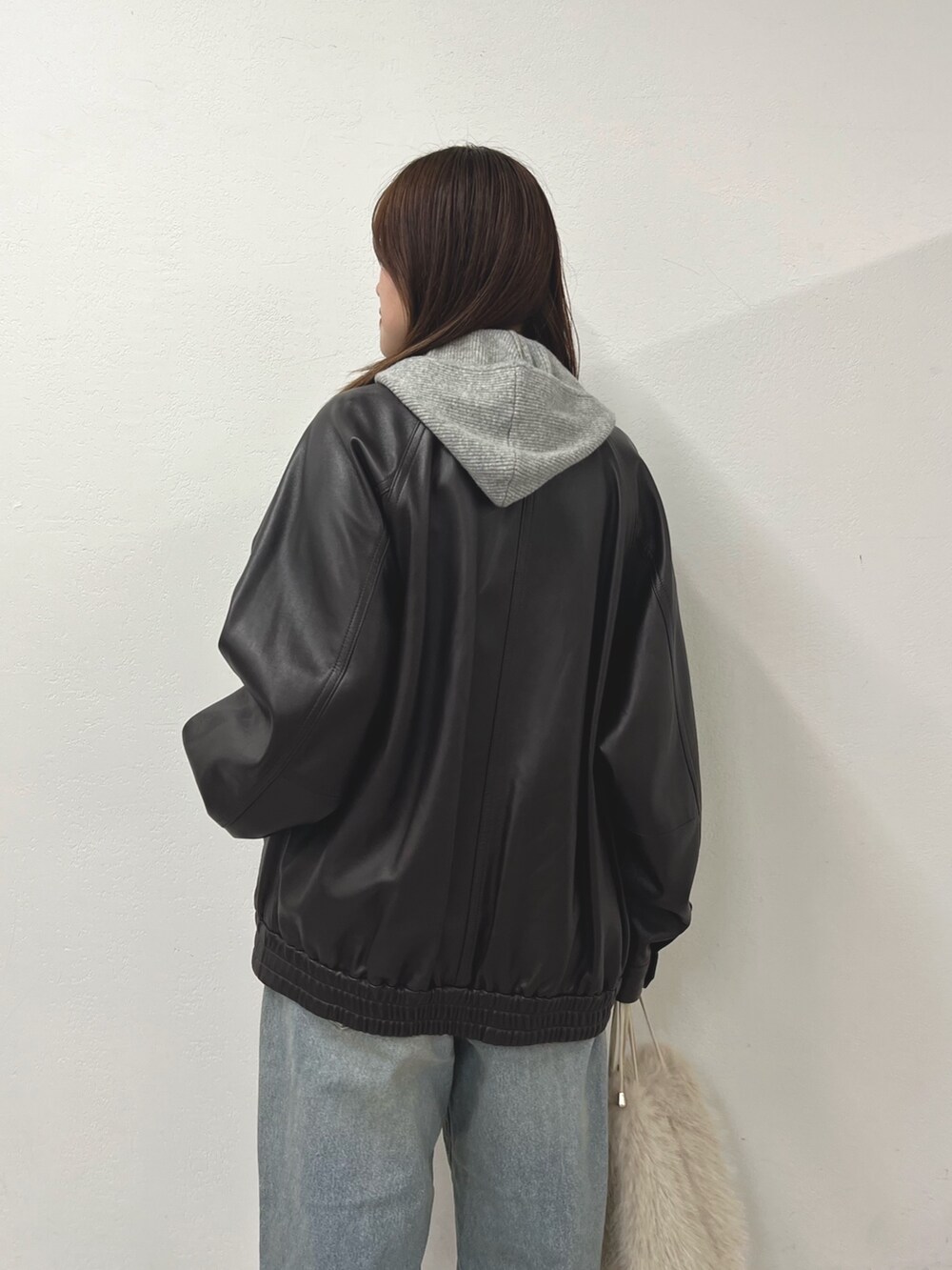 ブルー系のデニムパンツ、ブラウン系のブルゾン、ホワイト系のショルダーバッグを着用したレディースの秋コーディネートの2枚目の写真