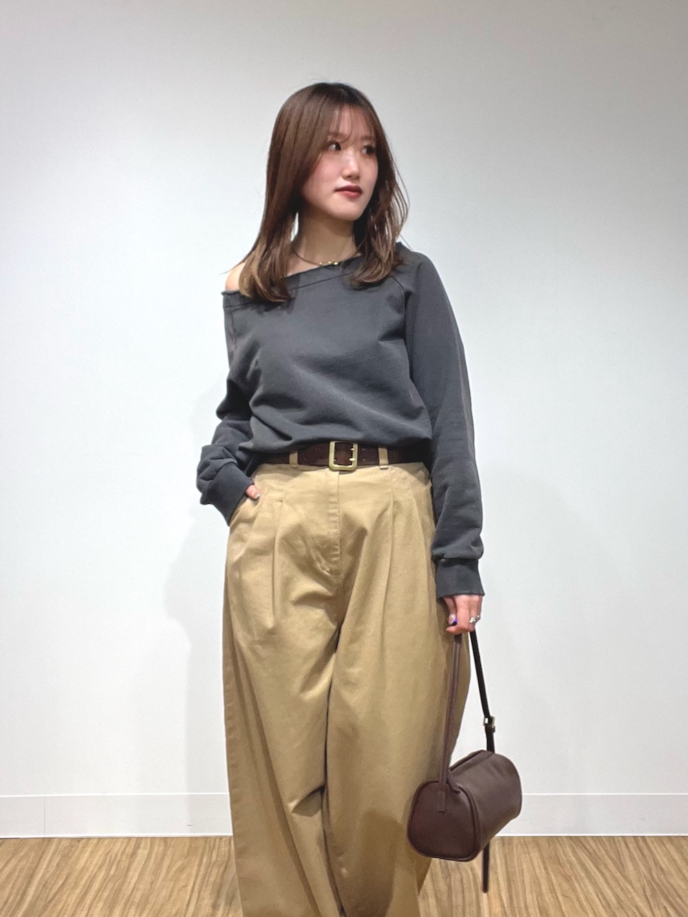 グレー系のスウェット、ベージュ系のチノパンツ、ブラウン系のショルダーバッグを着用したレディースの冬コーディネートの2枚目の写真