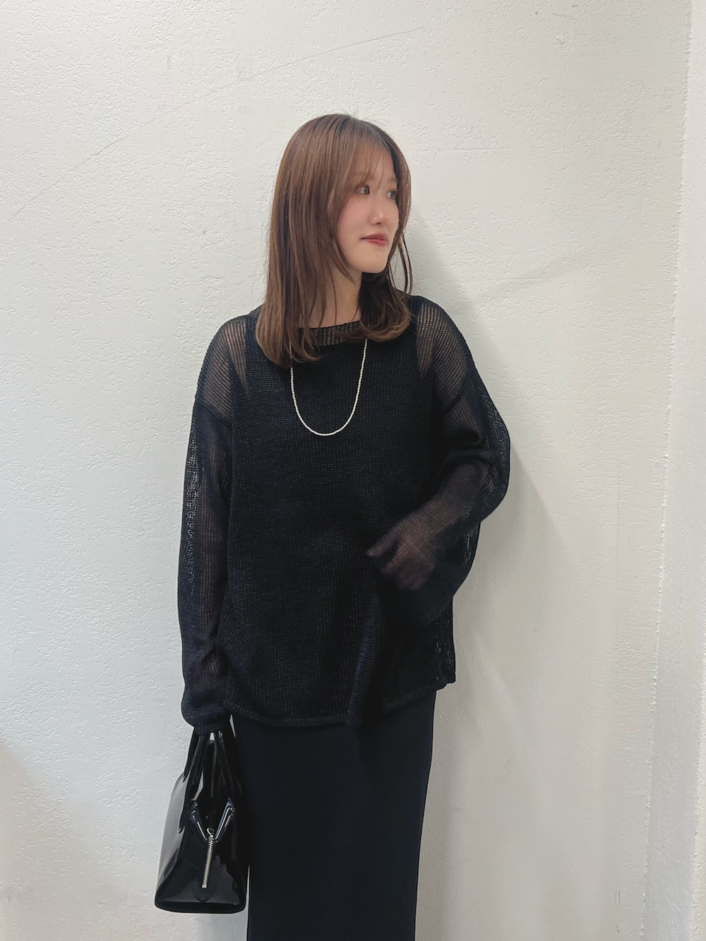 ブラック系のニット/セーター、ブラック系のスカート、ブラック系のボストンバッグを着用したレディースの冬コーディネートの2枚目の写真