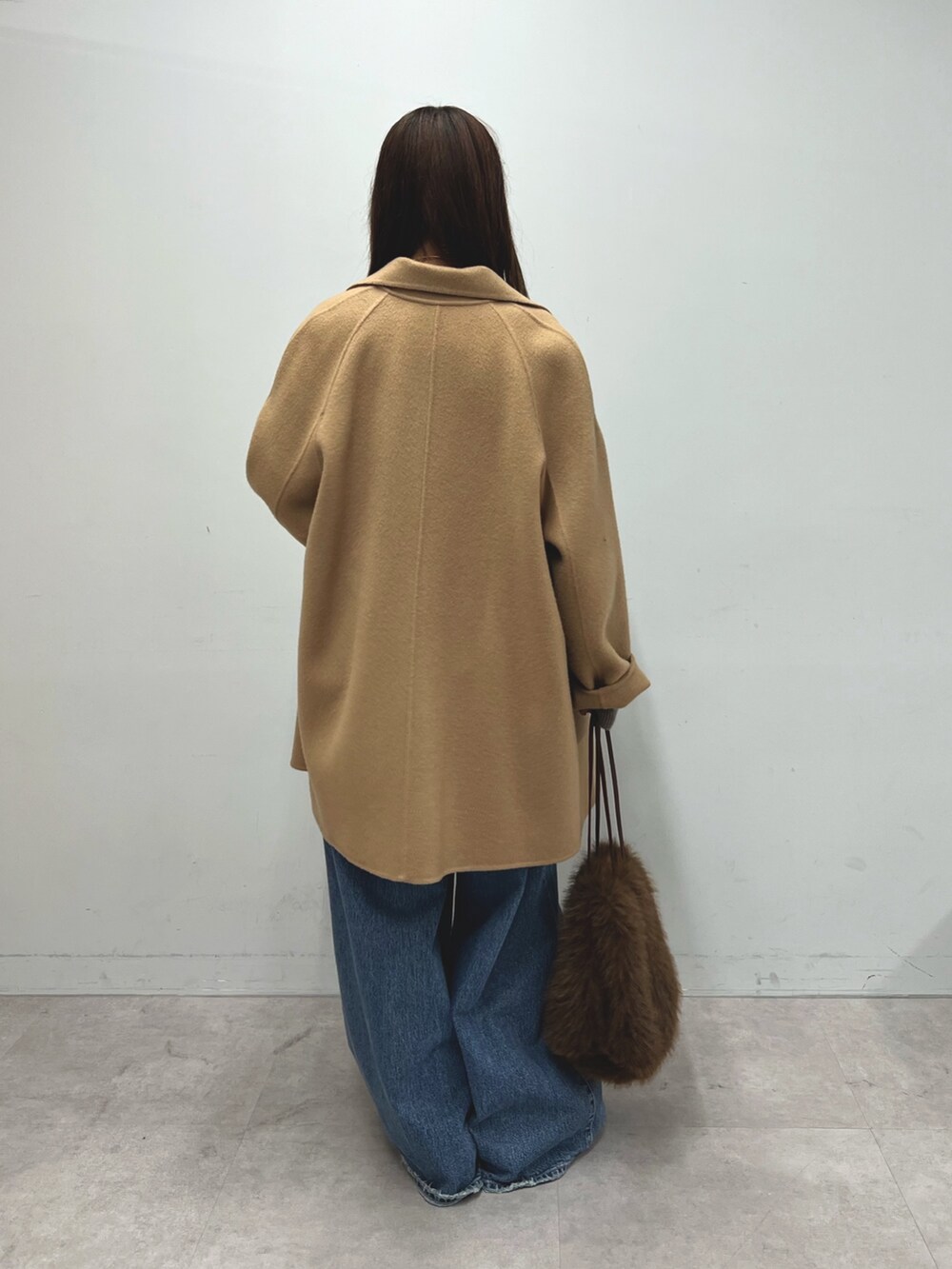 ブラウン系のニット/セーター、イエロー系のピーコート、ブルー系のデニムパンツを着用したレディースの秋コーディネートの5枚目の写真