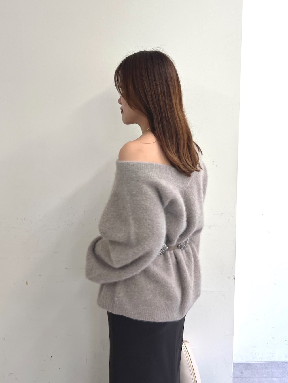 ブラウン系のニット/セーター、ブルー系のスカート、ベージュ系のクラッチバッグを着用したレディースの秋コーディネートの4枚目の写真