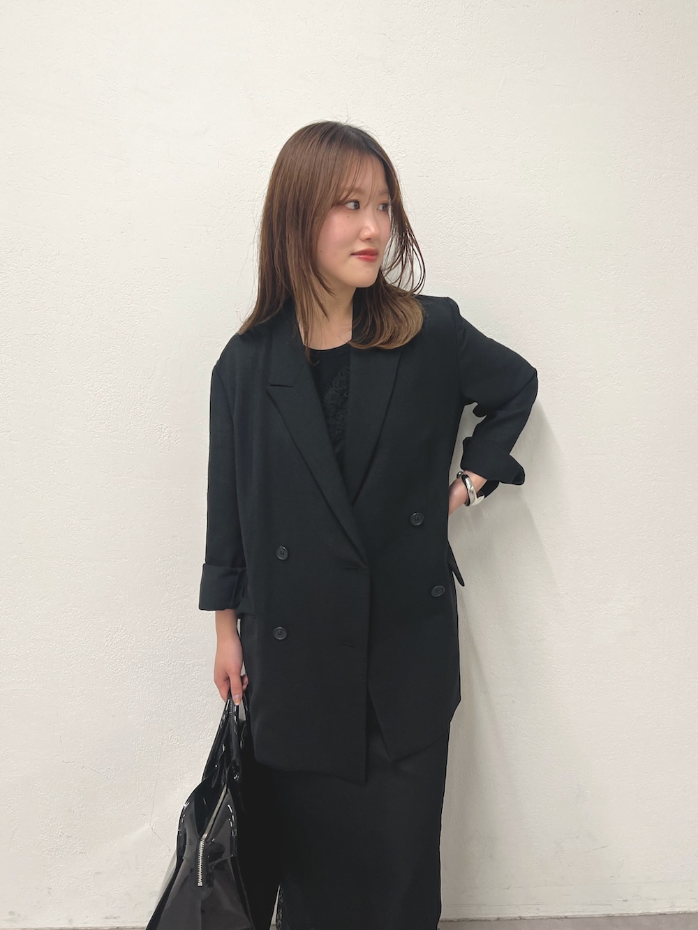 ブラック系のテーラードジャケット、ブラック系のキャミソール、グレー系のデニムパンツを着用したレディースの冬コーディネートの2枚目の写真