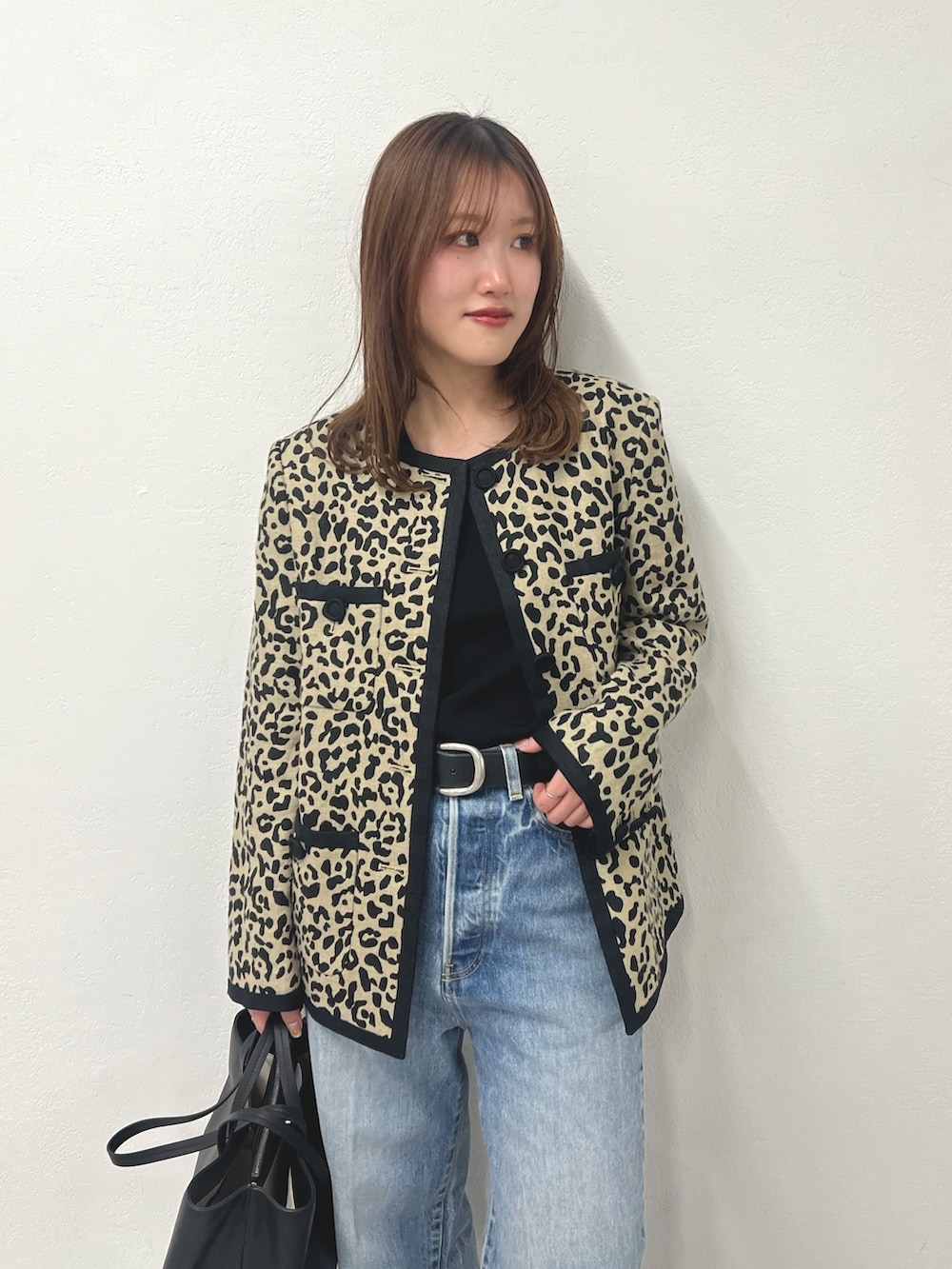 ブラック系のノーカラージャケット、ブルー系のデニムパンツ、ブラック系のトートバッグを着用したレディースの冬コーディネートの3枚目の写真