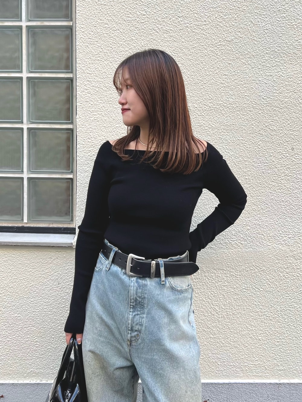 ブラック系のニット/セーター、ブルー系のデニムパンツ、ブラック系のボストンバッグを着用したレディースの冬コーディネートの2枚目の写真