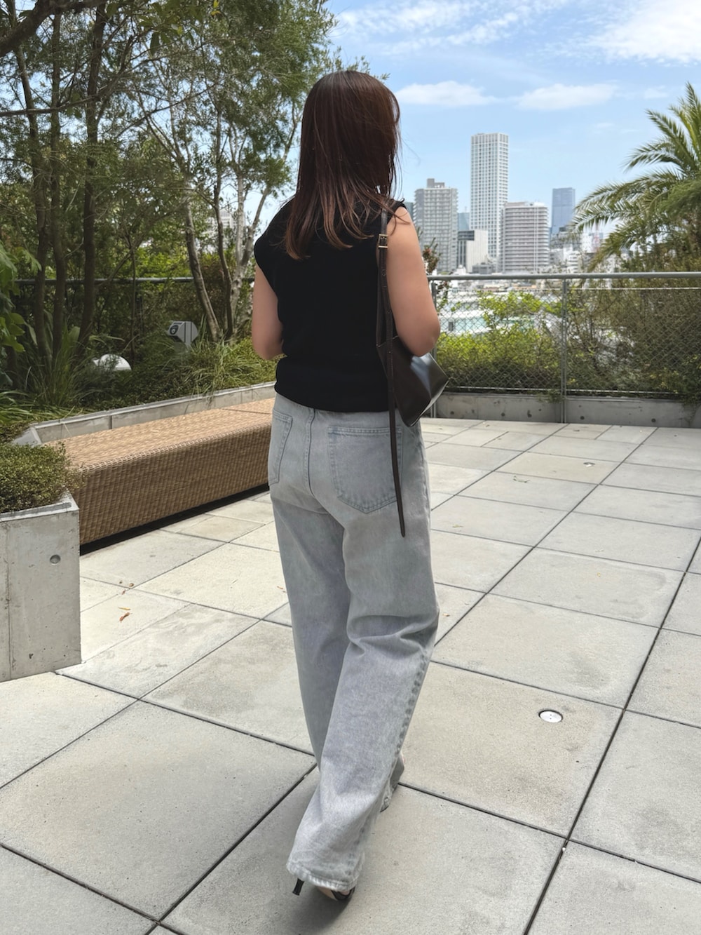 ブラック系のTシャツ/カットソー、グレー系のデニムパンツ、ブラウン系のショルダーバッグを着用したレディースの春コーディネートの2枚目の写真