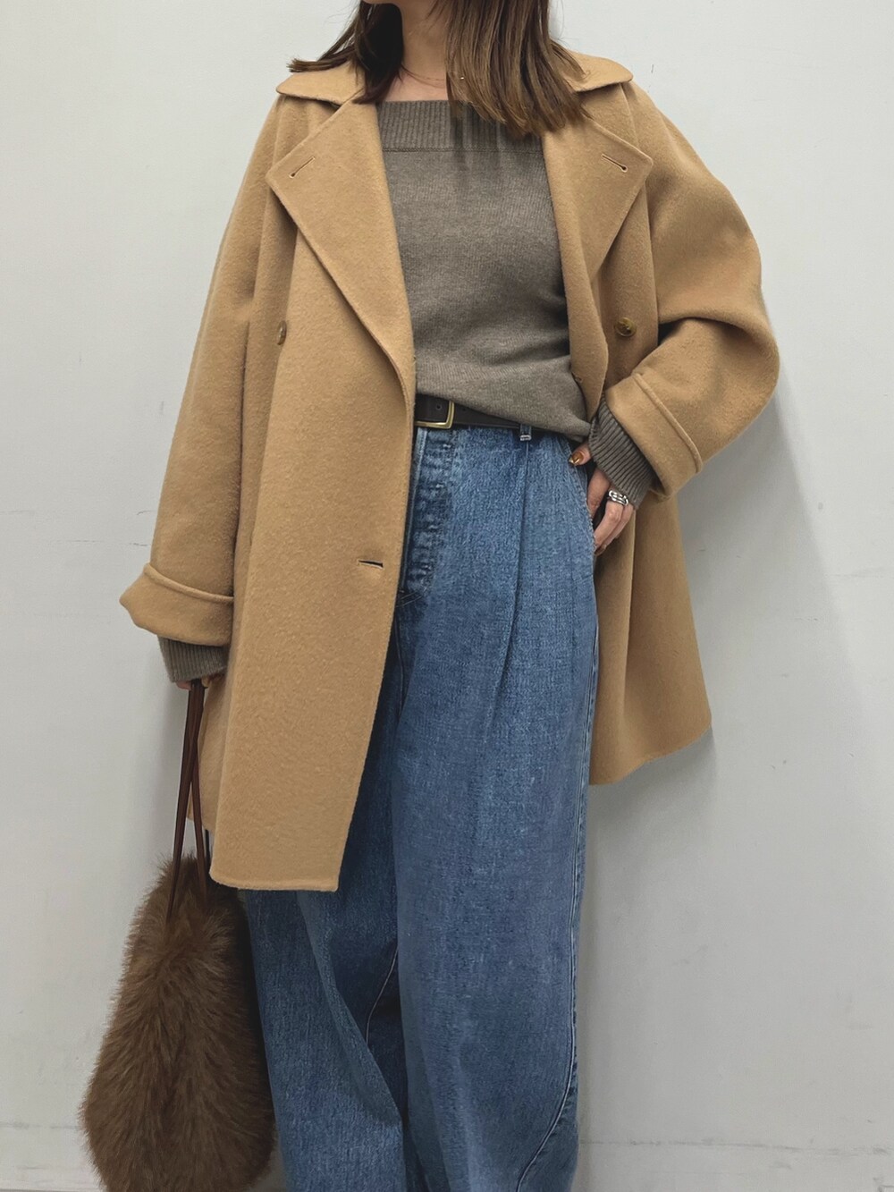 ブラウン系のニット/セーター、イエロー系のピーコート、ブルー系のデニムパンツを着用したレディースの秋コーディネートの4枚目の写真