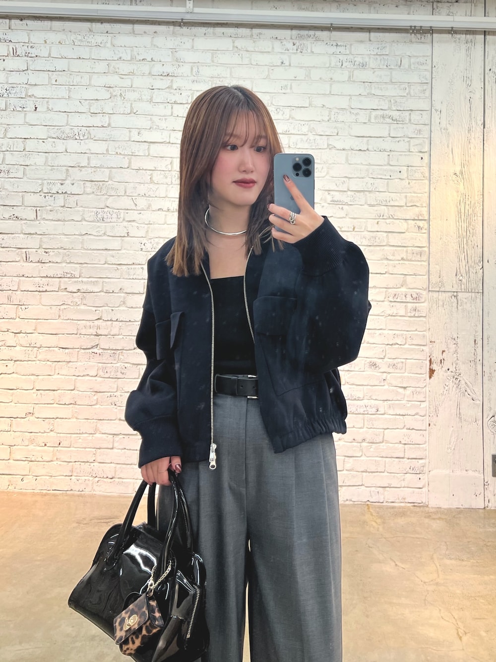 グレー系のスラックス、ブラック系のボストンバッグ、ブラック系のスニーカーを着用したレディースの冬コーディネートの2枚目の写真