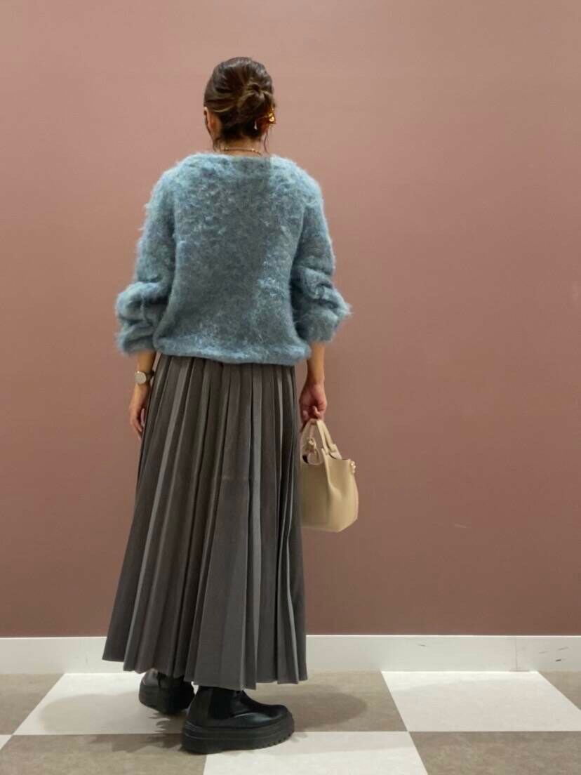 グリーン系のニット/セーター、ホワイト系のショルダーバッグ、グレー系のスカートを着用したレディースの秋コーディネートの2枚目の写真