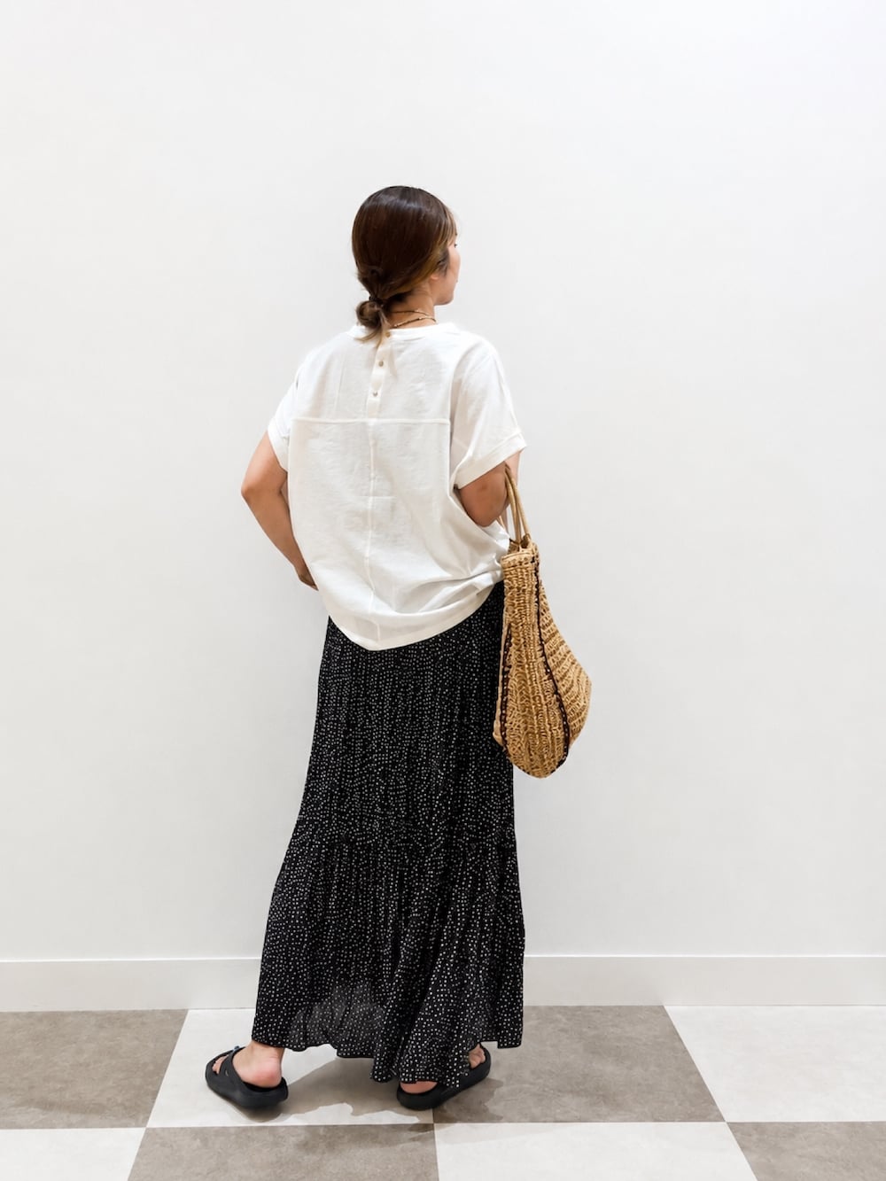 ホワイト系のTシャツ/カットソー、ベージュ系のトートバッグ、ブラック系のスカートを着用したレディースの夏コーディネートの2枚目の写真