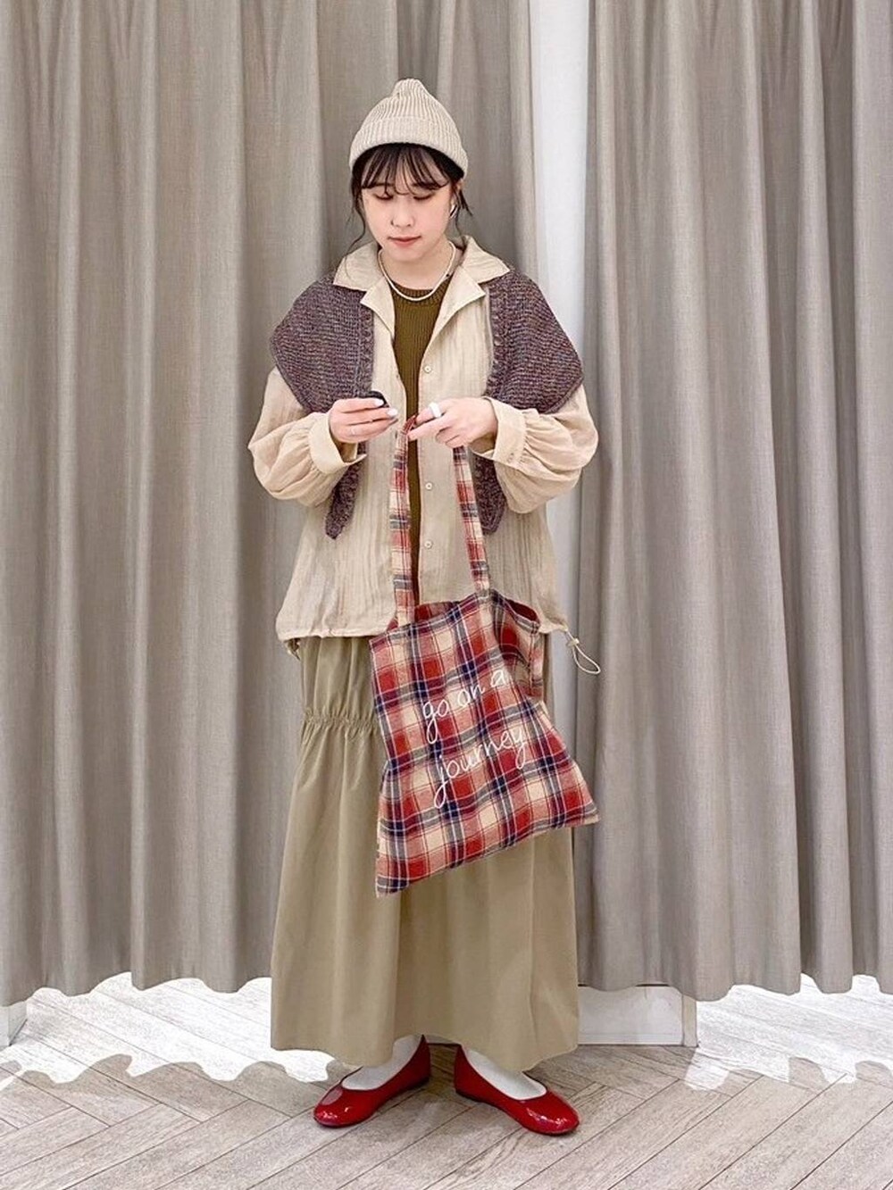 レッド系のパンプス、ベージュ系のナイロンジャケット、ベージュ系のワンピースを着用したレディースの秋コーディネートの8枚目の写真