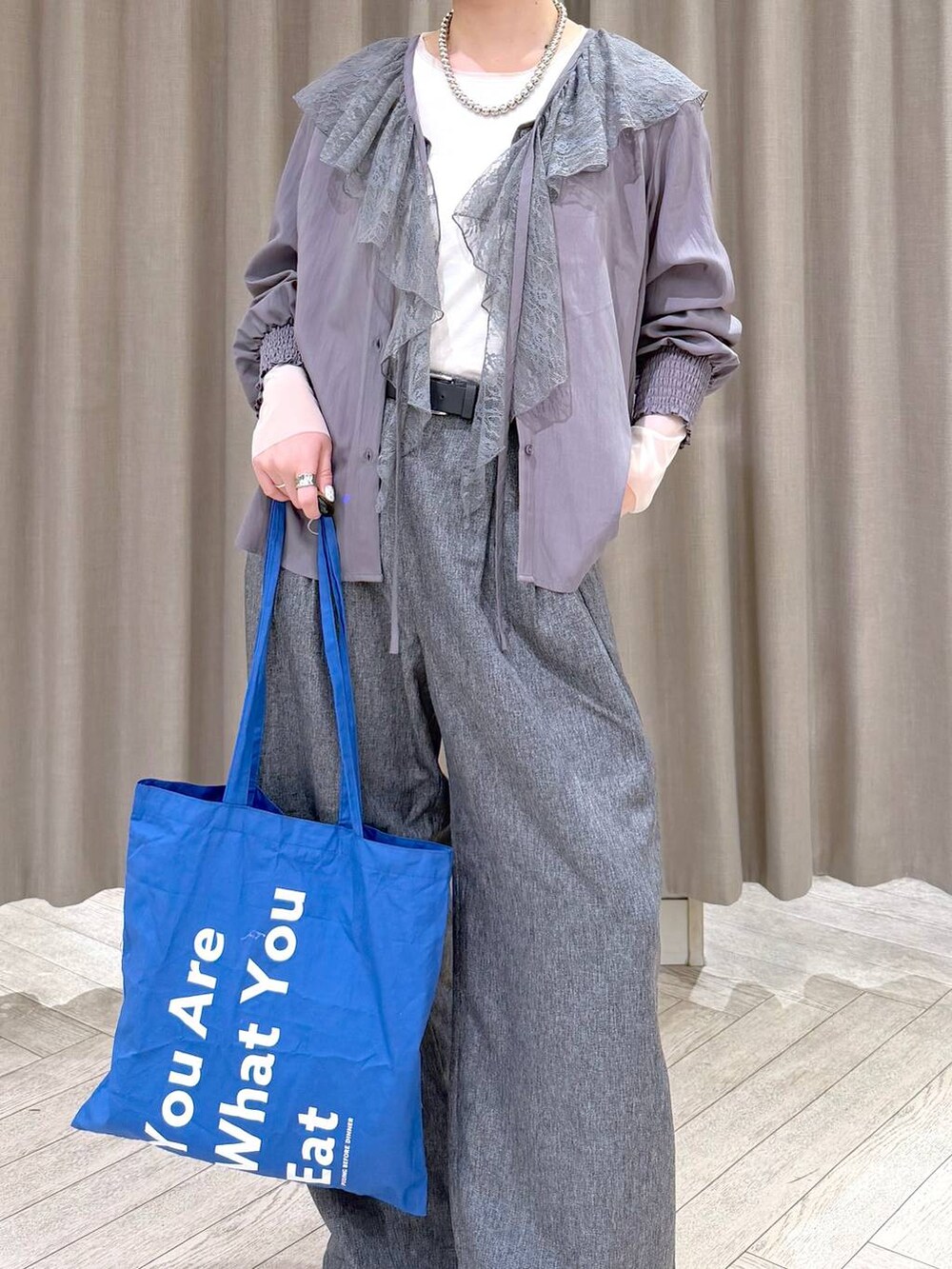 ホワイト系のTシャツ/カットソー、グレー系のスラックス、ブルー系のトートバッグを着用したレディースの冬コーディネートの6枚目の写真