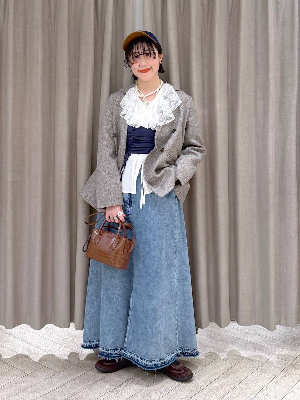 ベージュ系のテーラードジャケット、ブルー系のデニムスカート、ブラウン系のトートバッグを着用したレディースの冬コーディネートの9枚目の写真