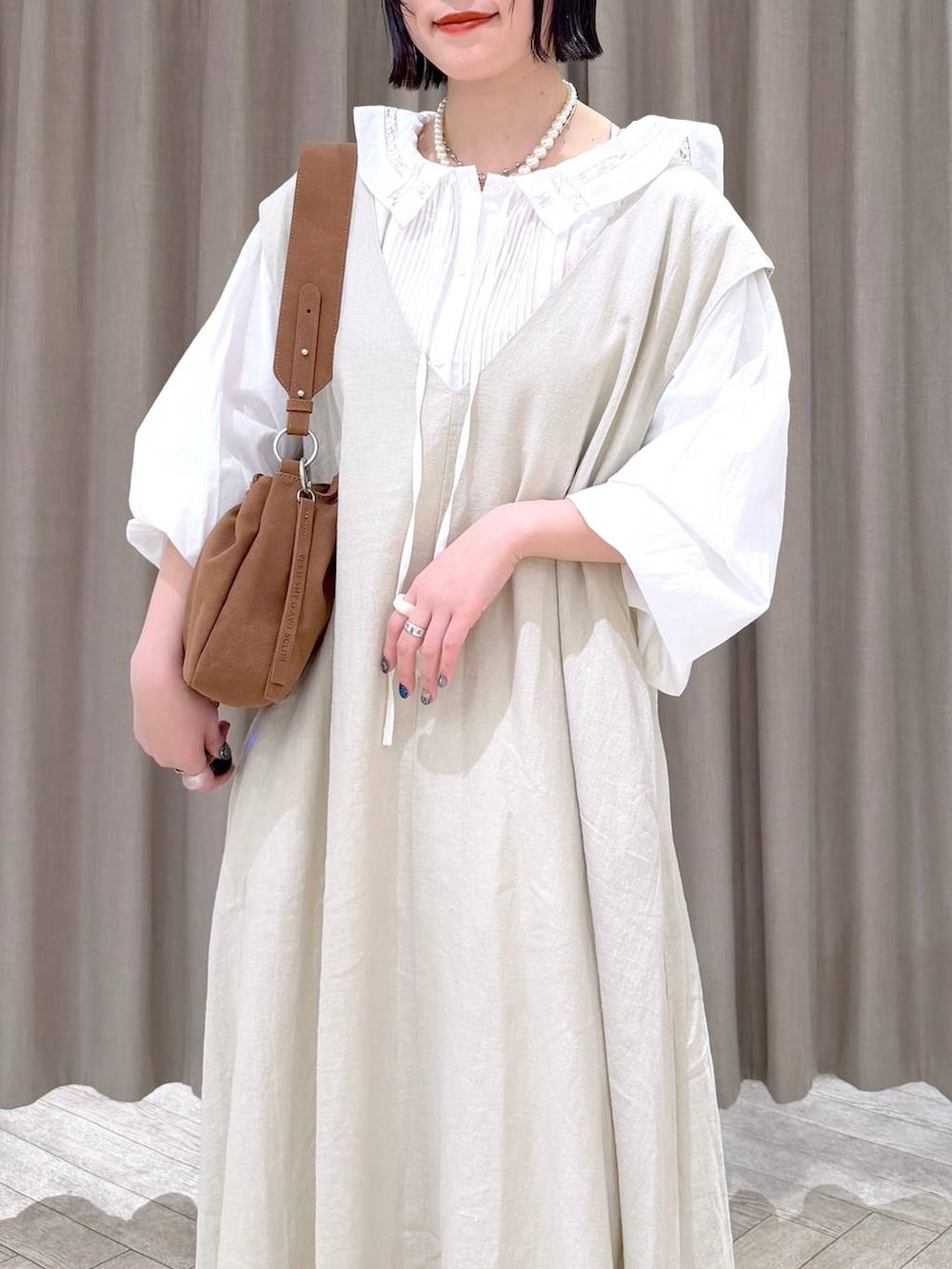 ベージュ系のジャンパースカート、ベージュ系のパンプス、ベージュ系のトートバッグを着用したレディースの冬コーディネートの6枚目の写真